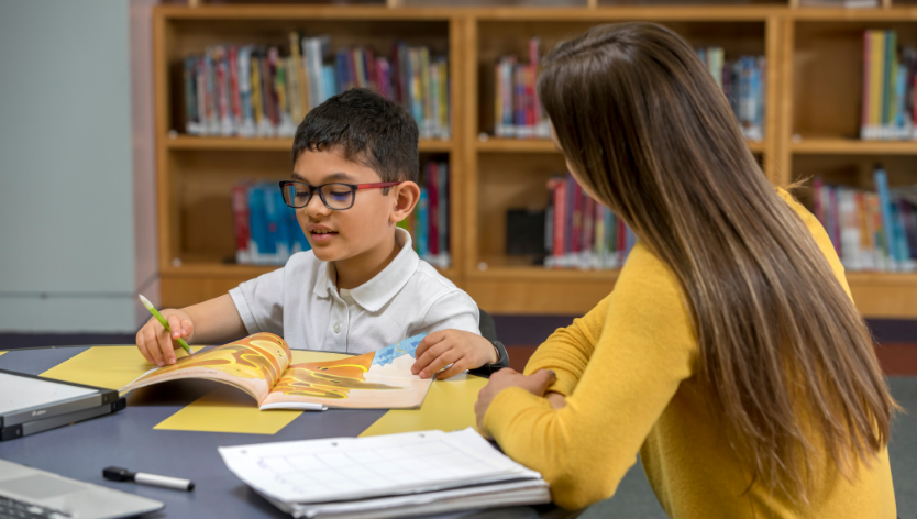 Child is being tutored in a library setting