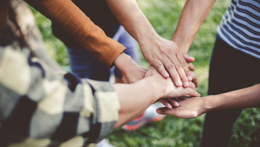 youth volunteers with their hands stacked on top of each other