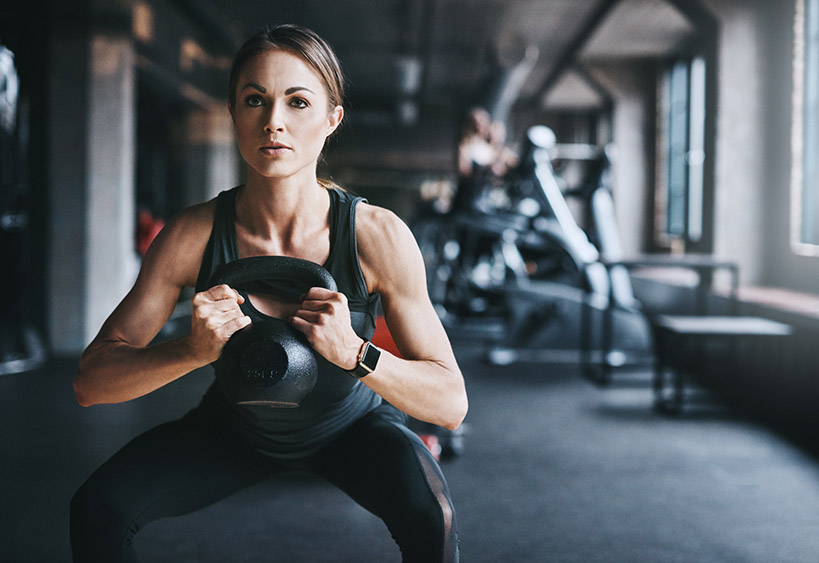 woman doing a squat holding a kettle bell