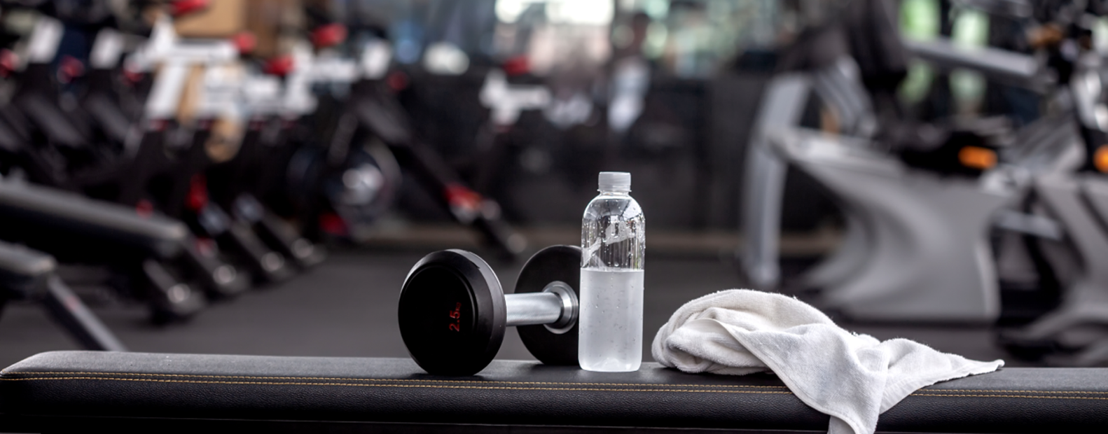 Weight, water bottle and towel on a bench. 