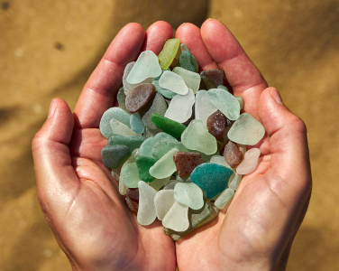 Hands holding colourful sea glass pieces.