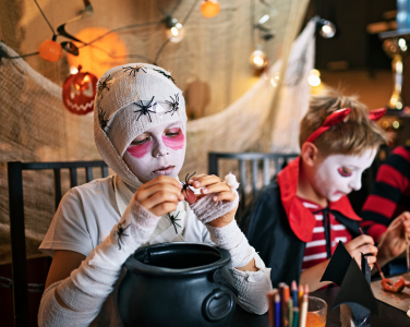 A child dressed as a mummy in a Halloween-themed setting.