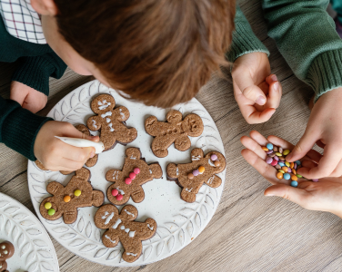 Children decorating gingerbread cookies with icing and candy.