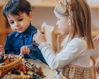 Children playing at a table with toy animals.