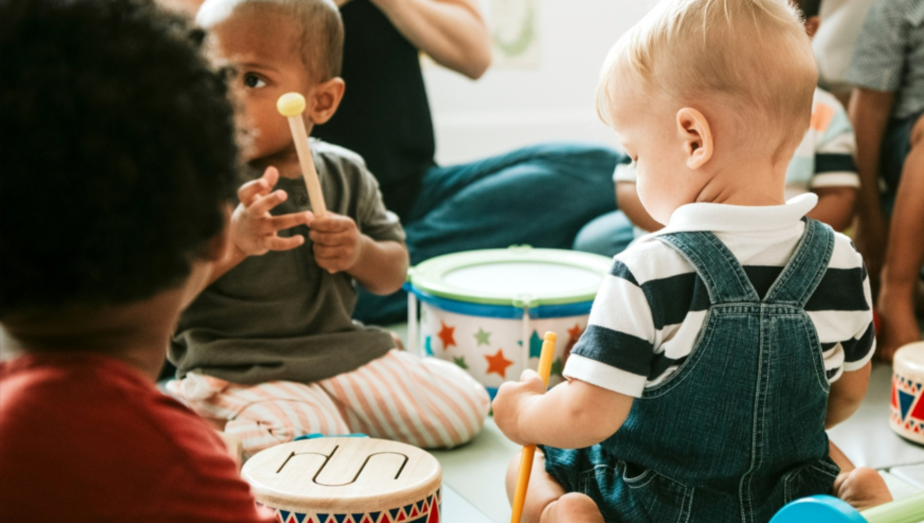 Children playing with colorful drums and instruments in a group setting.