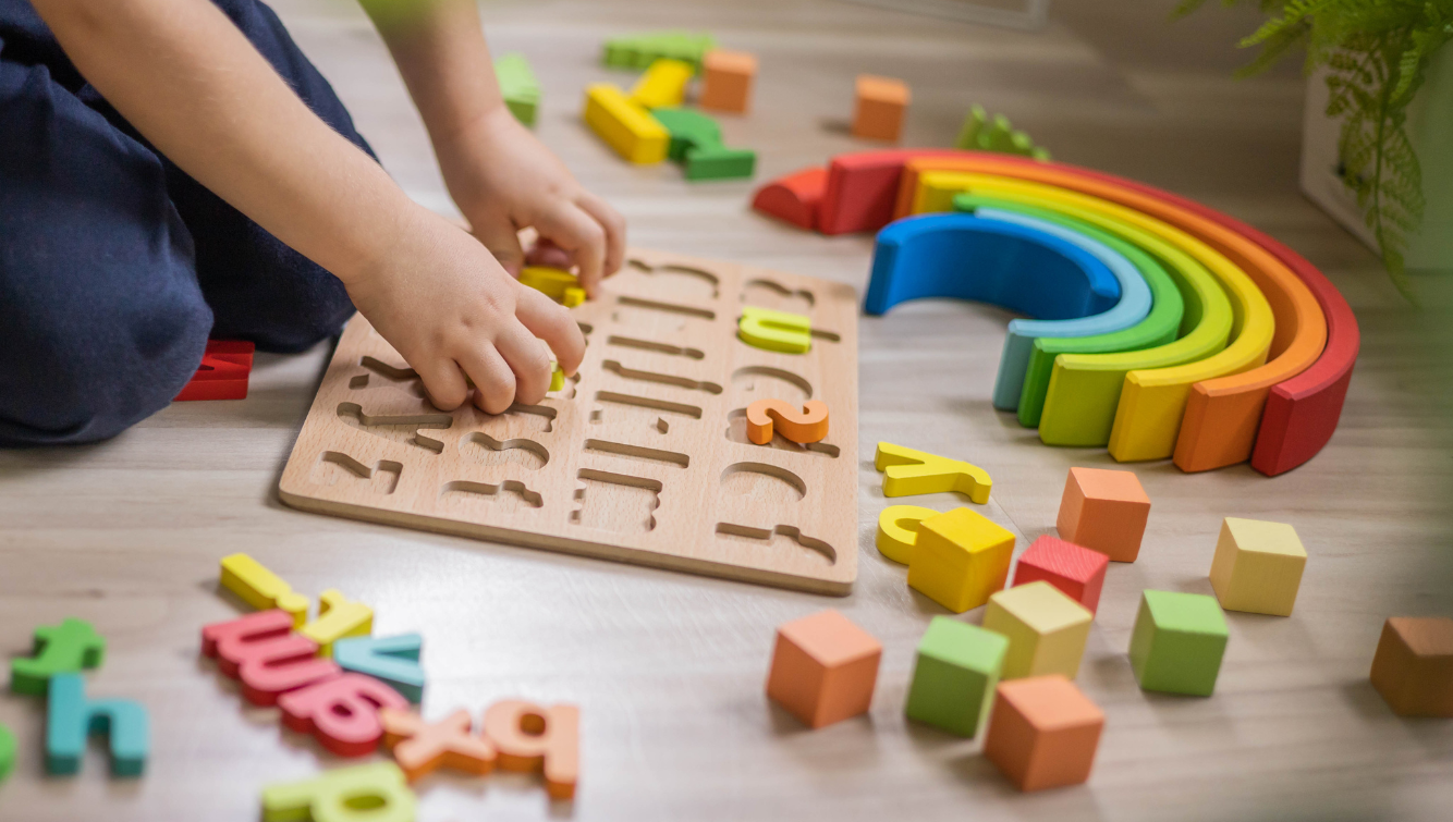 Child assembling an alphabet puzzle with colorful blocks and rainbow arches.