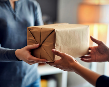 Two people exchanging a brown paper-wrapped package.