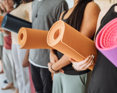 People holding rolled-up yoga mats.