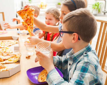 Children eating pizza around a table.