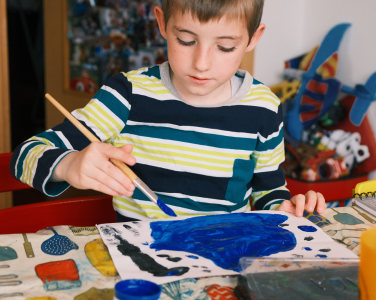 Child holding a paint brush over a blank paper.