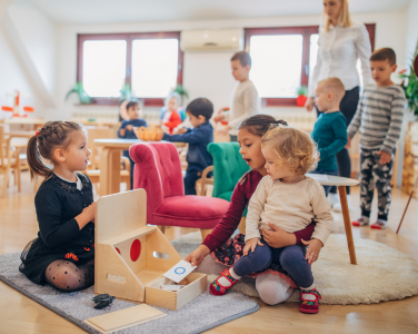 Children playing with toys in a bright classroom.