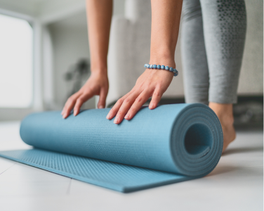 Person rolling out a yoga mat on the floor