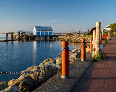 Waterfront scene with a pathway and a blue building on stilts over the water.