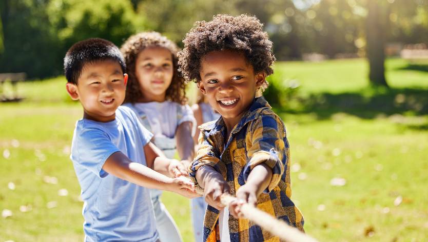 young children playing outside and pulling on a rope