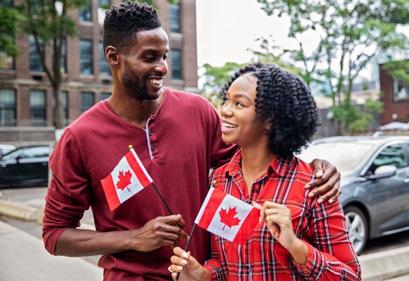 A smiling couple holding Canadian flags.