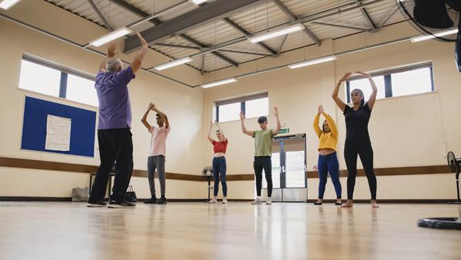 people in an exercise class reaching thier arms up
