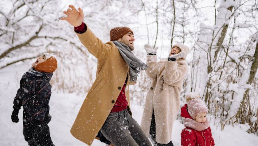 Family of four enjoying the snow falling outdoors