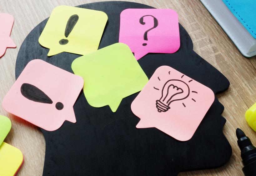 Head silhouette with light bulb and exclamation Post-it notes