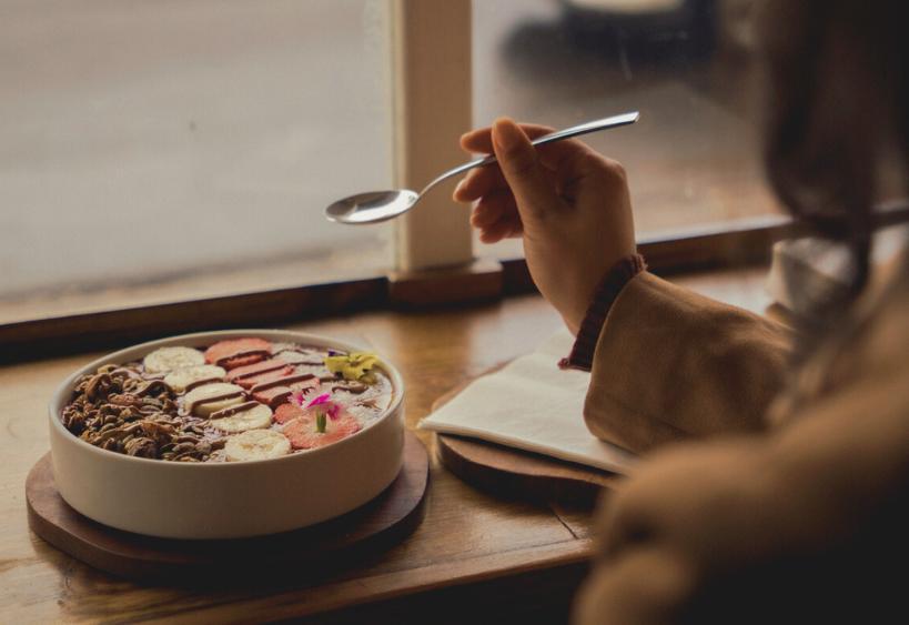 Woman holding spoon beside smoothie bowl