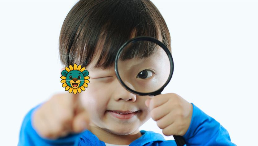 Little boy pointing finger and looking through magnifying glass