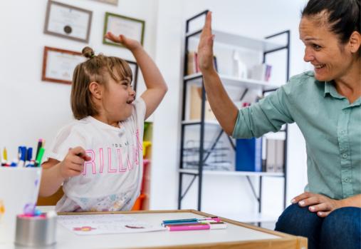 teacher and small girl with Down syndrome giving high-five