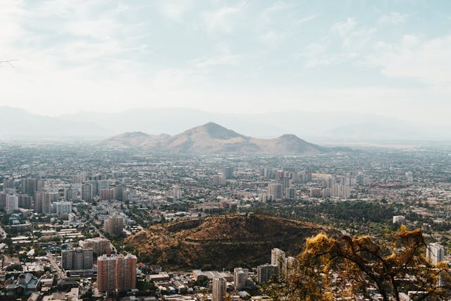 Aerial view of Santiago, Chile with mountains in the background and cityscape below.