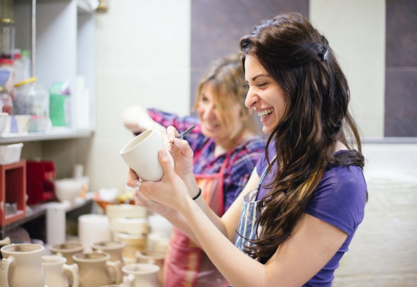 People painting a piece of pottery