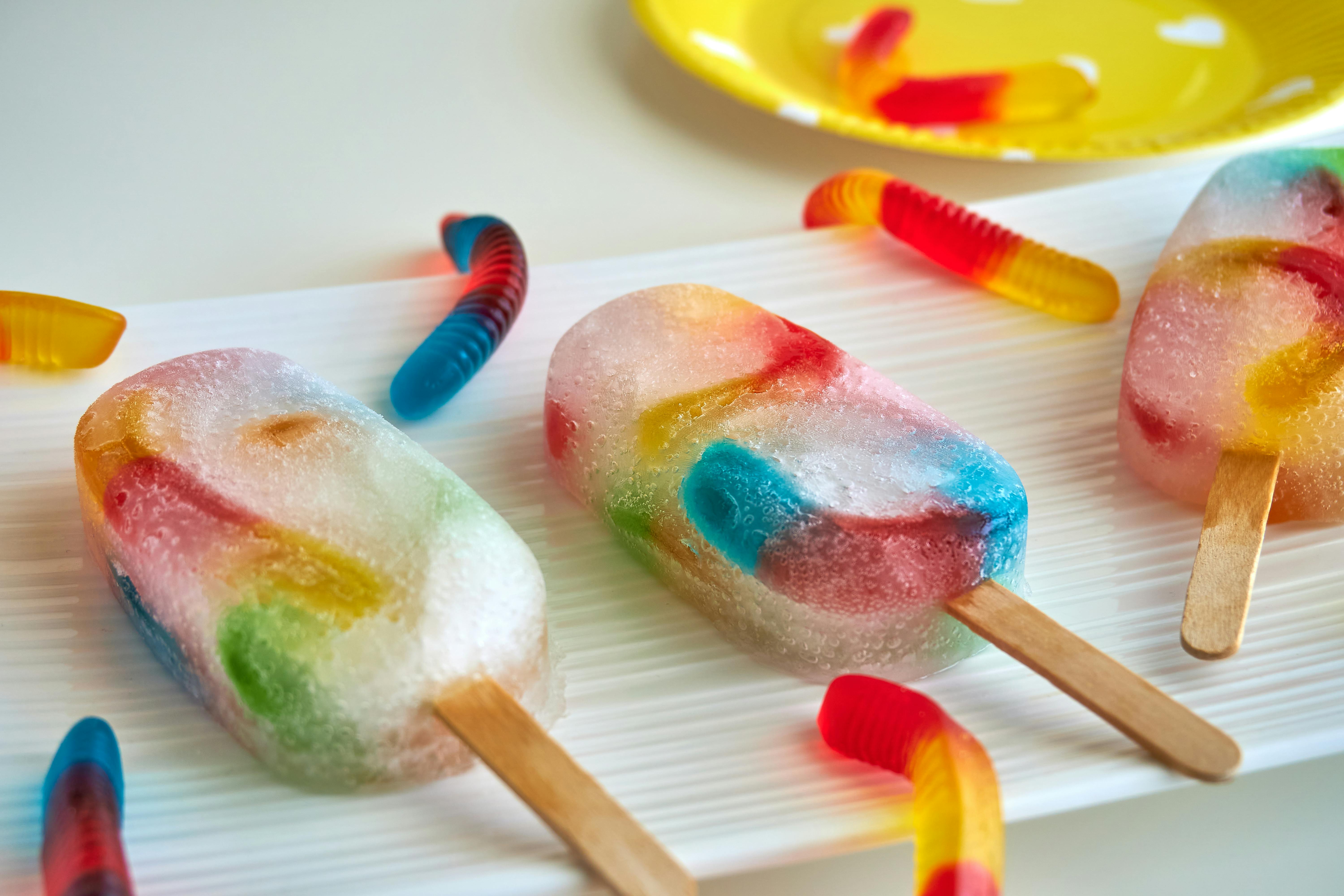 popsicles with gummy worms lying on a counter