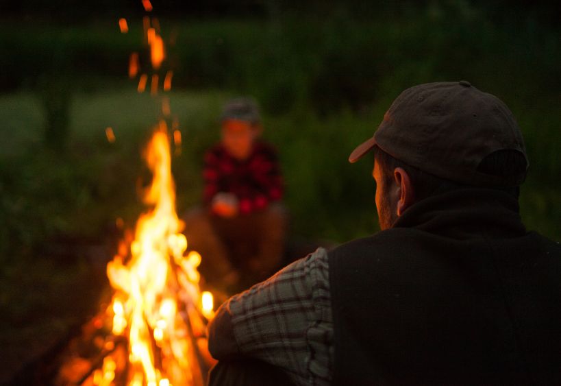 back of man staring into a fire