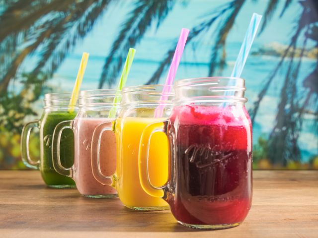 Vibrant smoothies in mason jars with colorful straws, perfect for a summer refreshment.