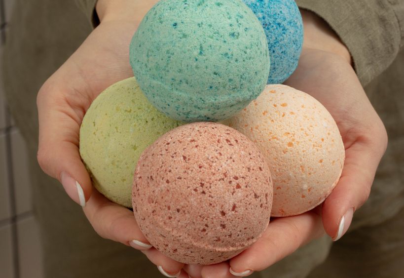 Colourful bath bombs are being held in a person's hands.