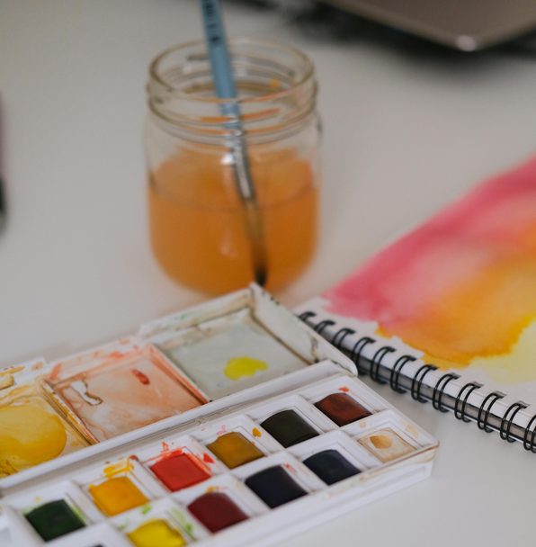 white table with watercolour palette and watercolour book open