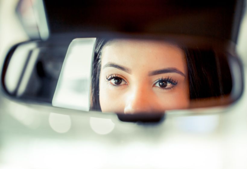 woman looking in the rear view mirror