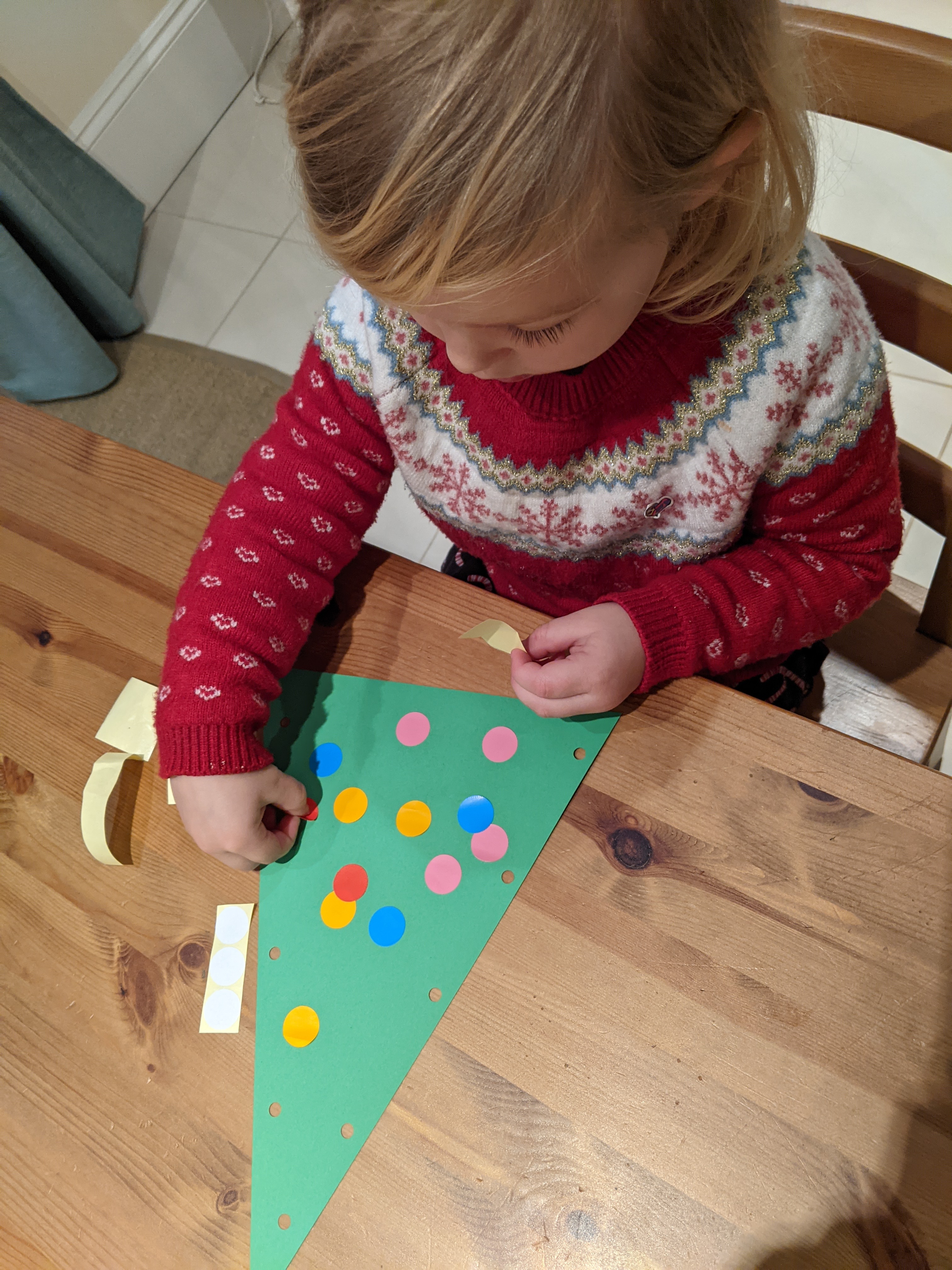 girl putting stickers on a paper tree