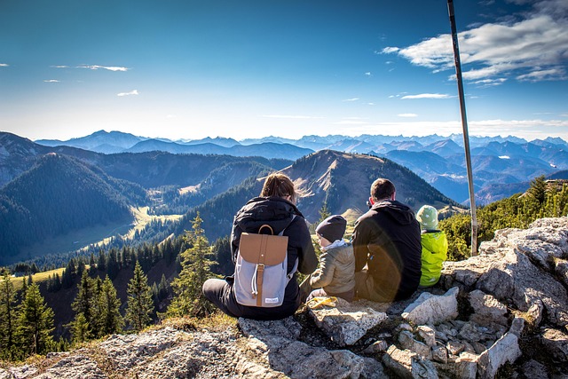 back of a family sitting at the top of a mountain