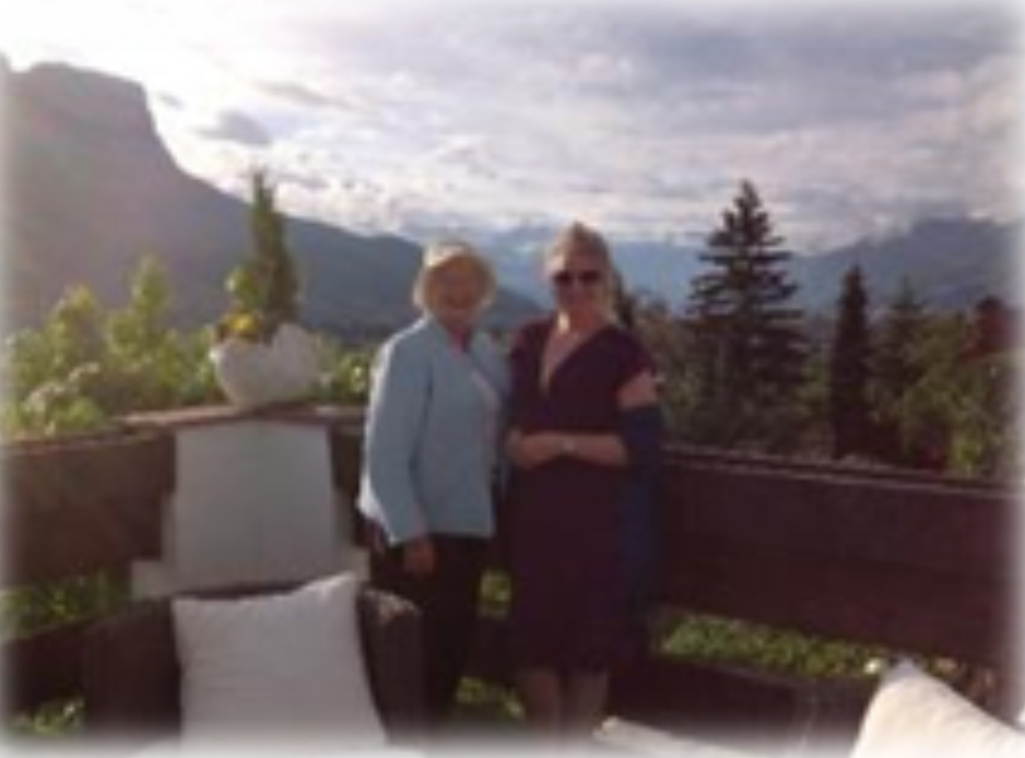 two women standing at viewpoint with mountains in background