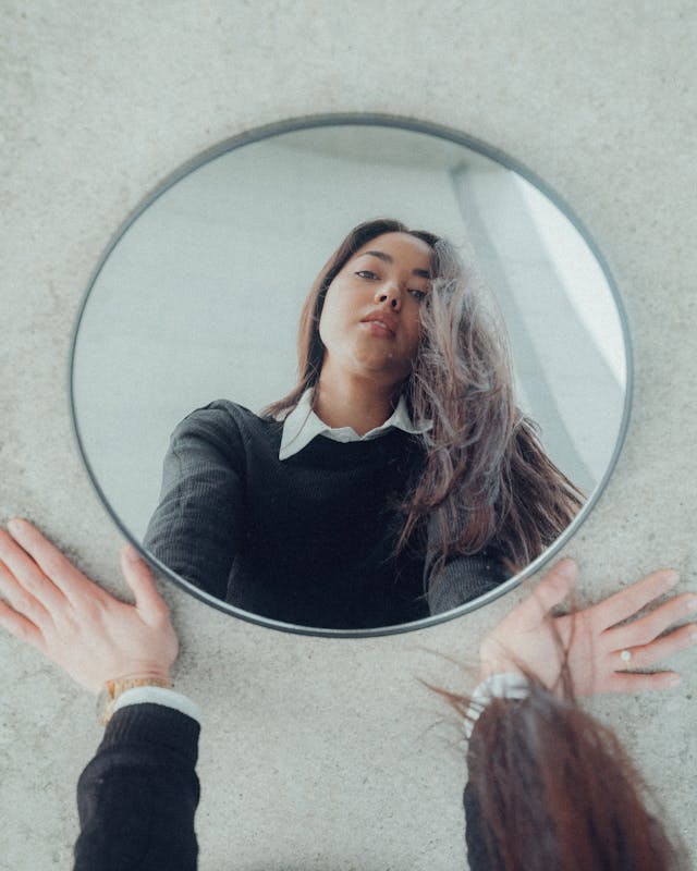 Reflection of Young Woman in Black Sweater in Mirror on Floor