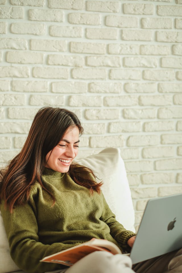 Woman with a Laptop and a Book sitting in the Living Room