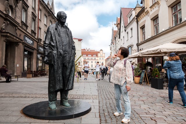 A woman standing next to a statue of a man