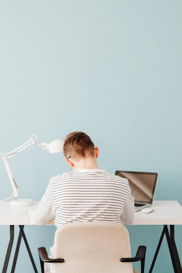 Teenage Boy Sitting Behind His Desk and Studying