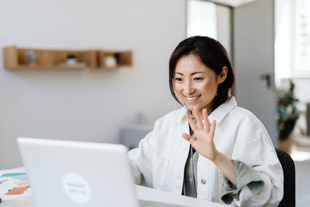 woman waving at a laptop
