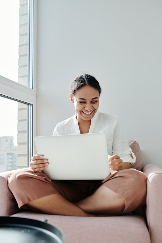 woman looking and smiling at a laptop