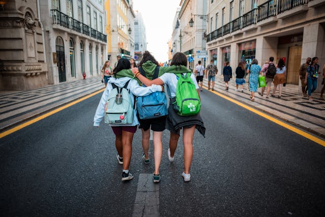 back of three teens walking down the middle of a road
