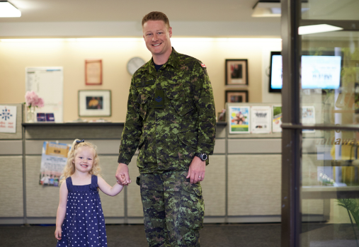 member in uniform holding daughters hand