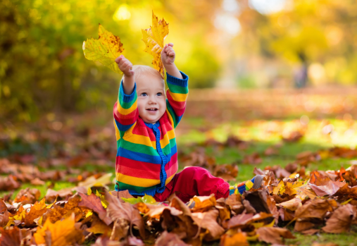 baby playing in pile of leaves