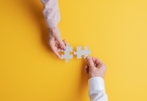 2 puzzle pieces being connected by a woman & a man's hands