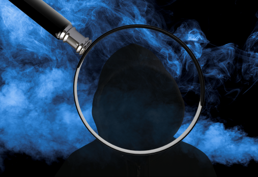 a blue smokey background with a silhouetted hooded figure in the centre with a magnifying glass on it 
