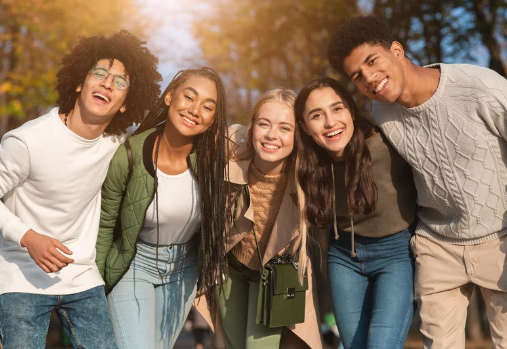 a group of teens smiling for the camera in front of some fall trees