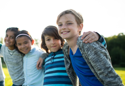 A group of youth arm in arm outside in a grassy area