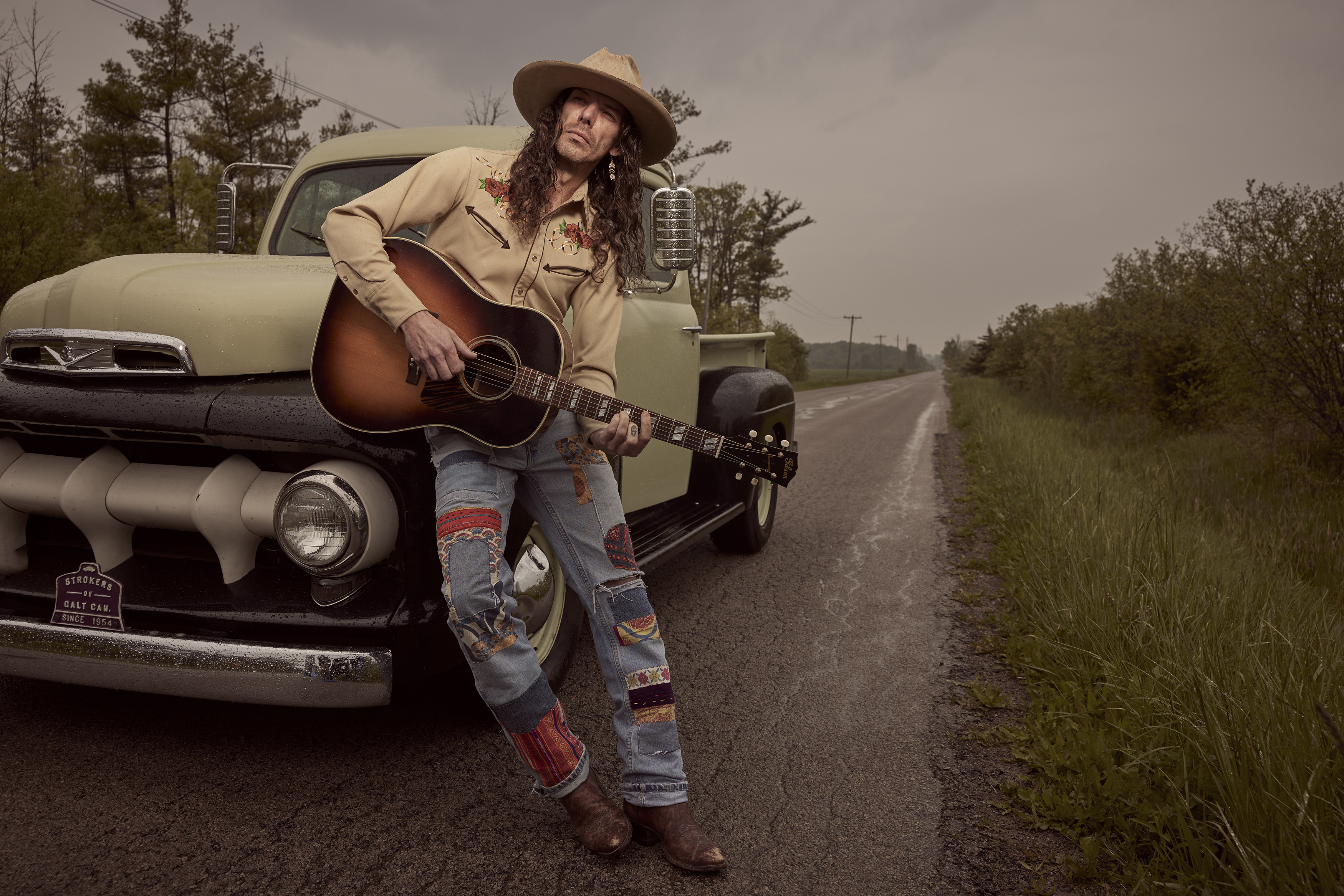 Kyle McKearney holding a guitar leaning on a vintage truck